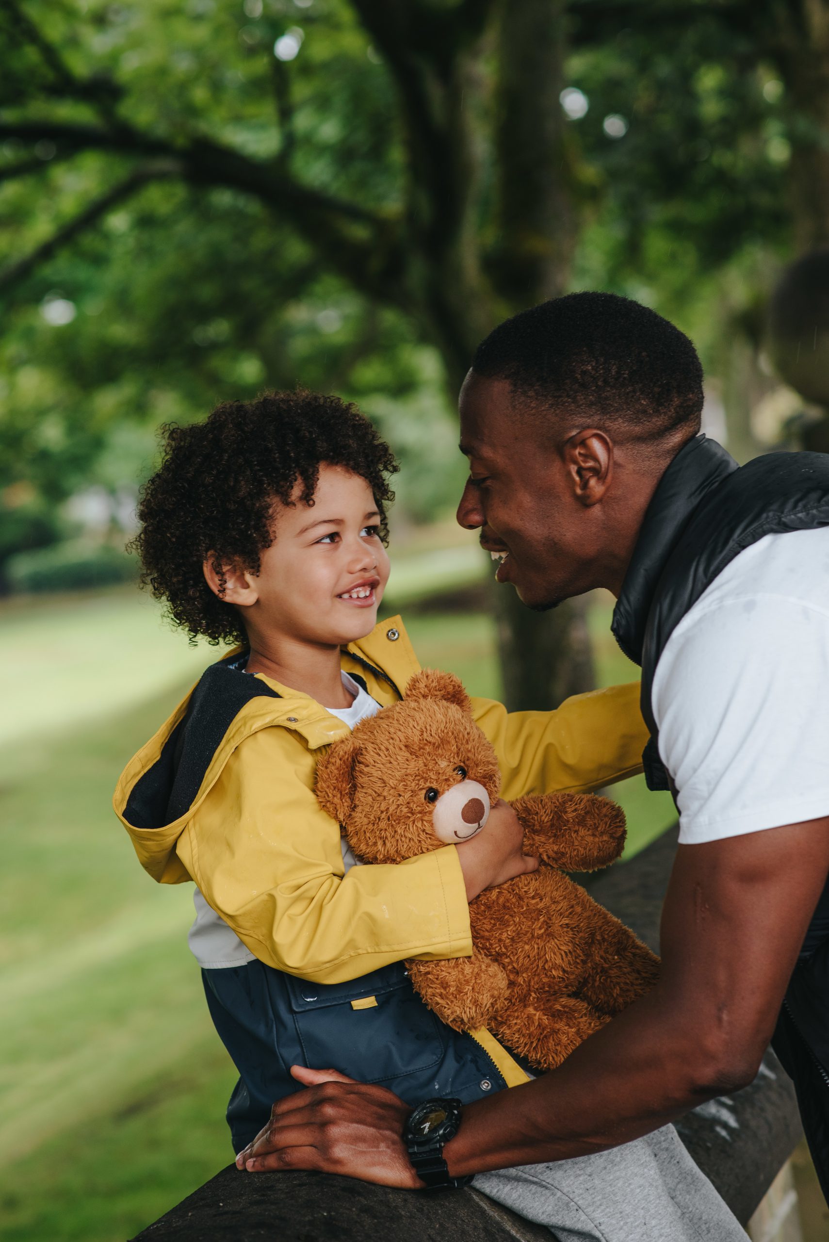 A vertical shot of an African-American child and his father in the park